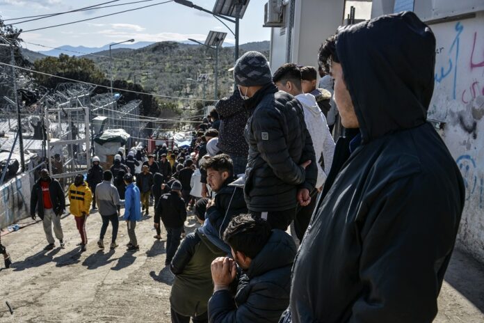migranti zhromadenie, policajti hliadkovanie brána uteèenecký tábor Moria na ostrove Lesbos